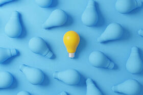 One yellow lightbulb amongst a plethora of blue lightbulbs